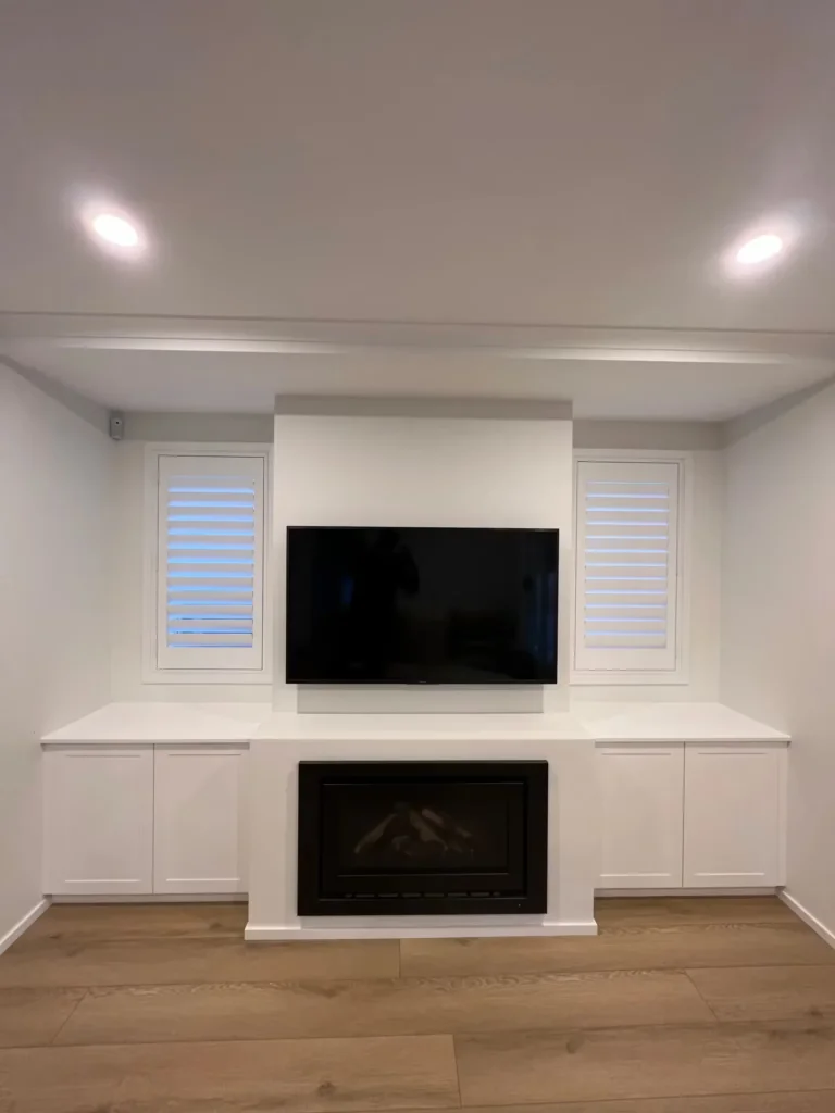 Custom white shaker-style cabinetry and integrated fireplace surround with wall-mounted television, a premium residential internal fit-out